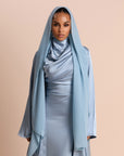 Woman wearing a light blue abaya against a beige background