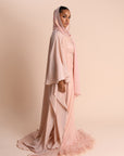 Woman wearing a pink hijab and dress against a beige background