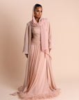 Woman wearing a pink hijab and dress against a beige background