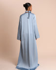 Woman wearing a light blue Abaya on a beige background