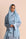 Woman wearing a light blue hijab and outfit against a beige background