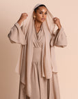 Woman wearing a beige outfit with a matching Hijab against a beige background