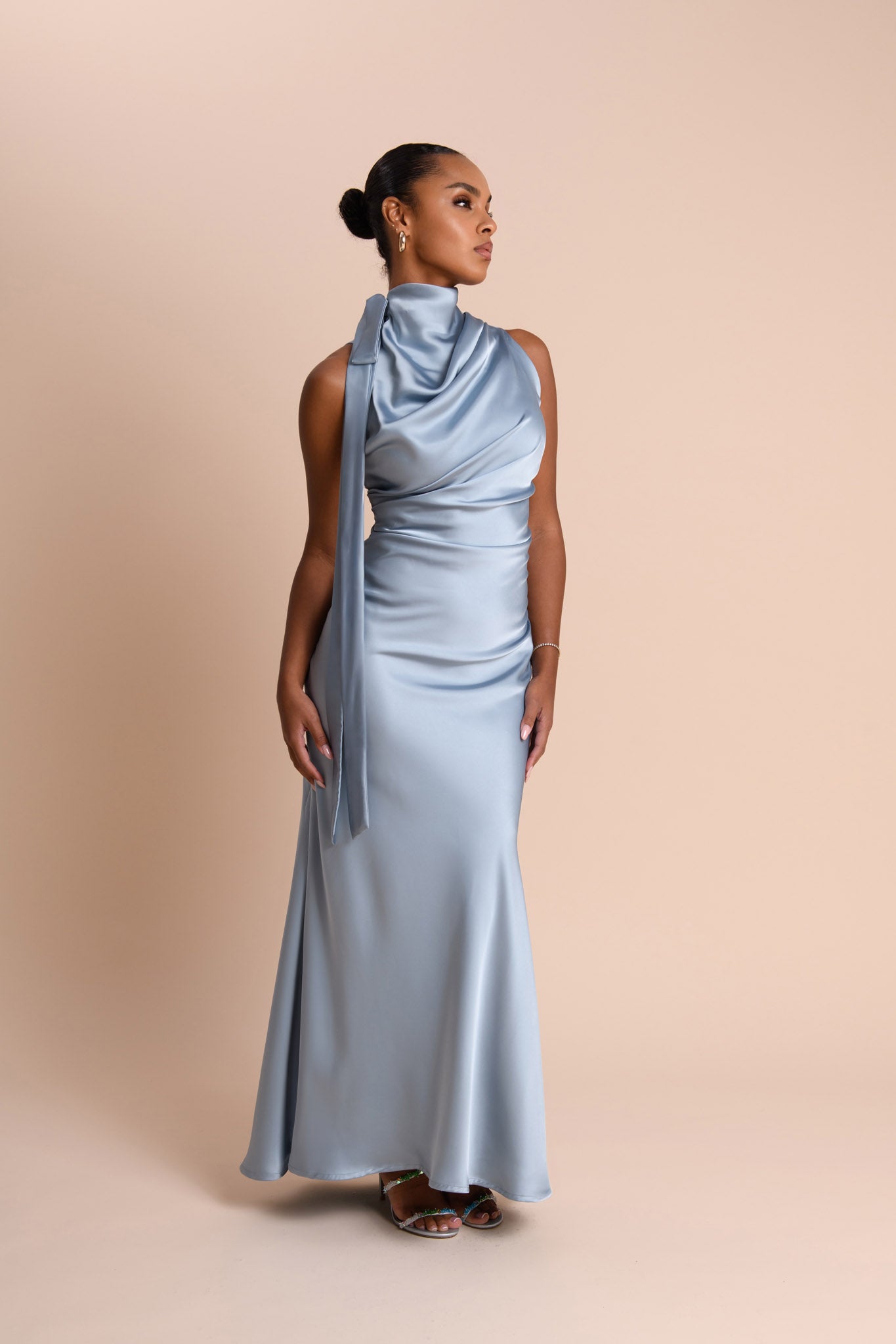 Woman wearing a light blue gown with a draped neckline against a beige background