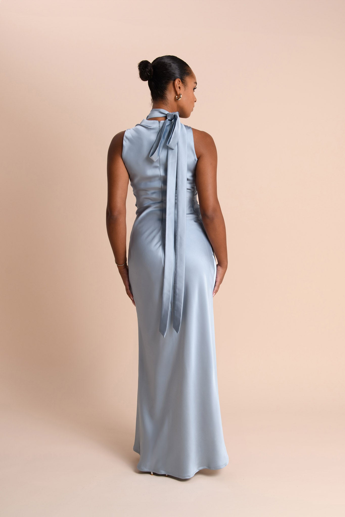 Woman wearing a light blue gown with a long train on a beige background