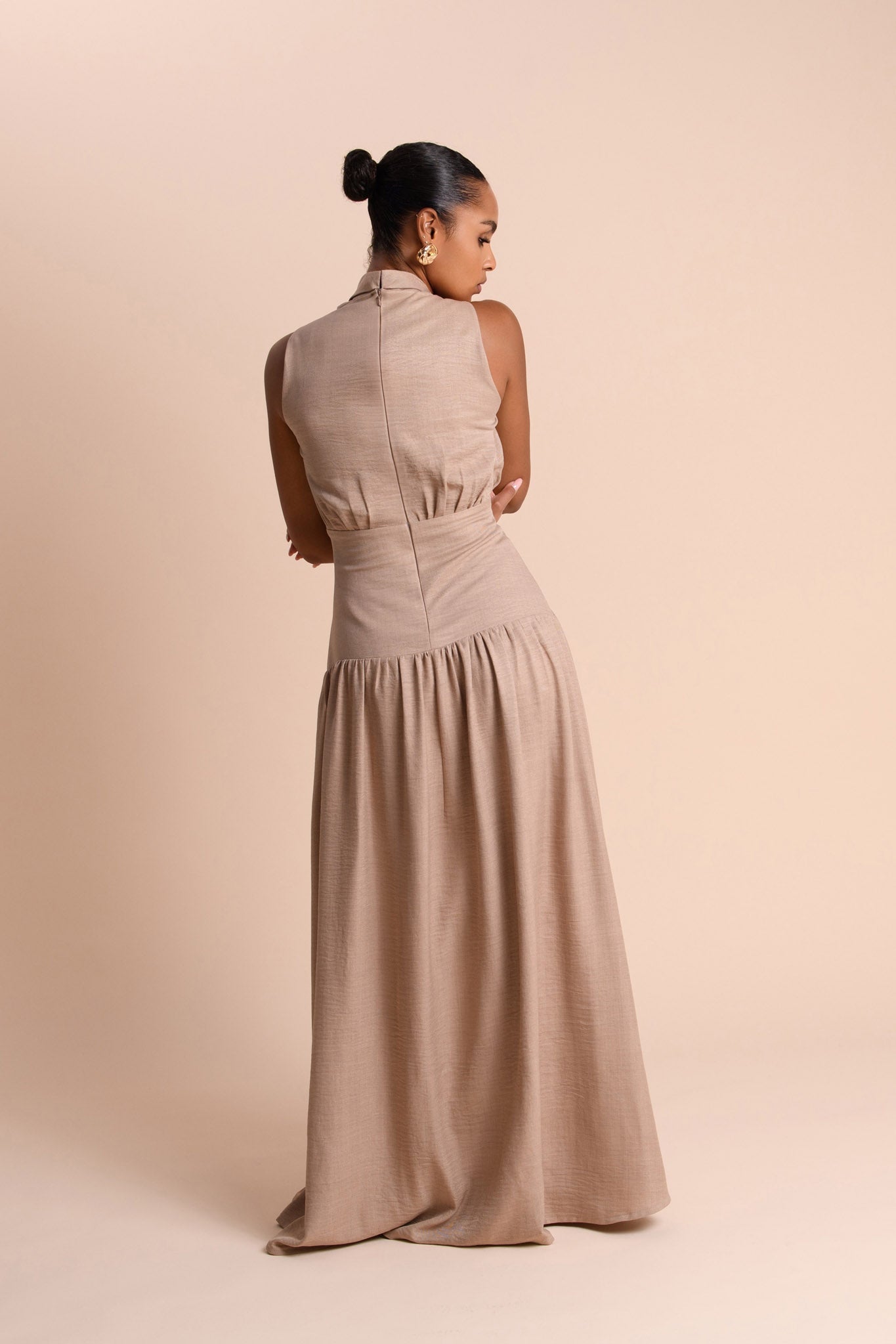 Woman wearing a beige sleeveless dress against a beige background