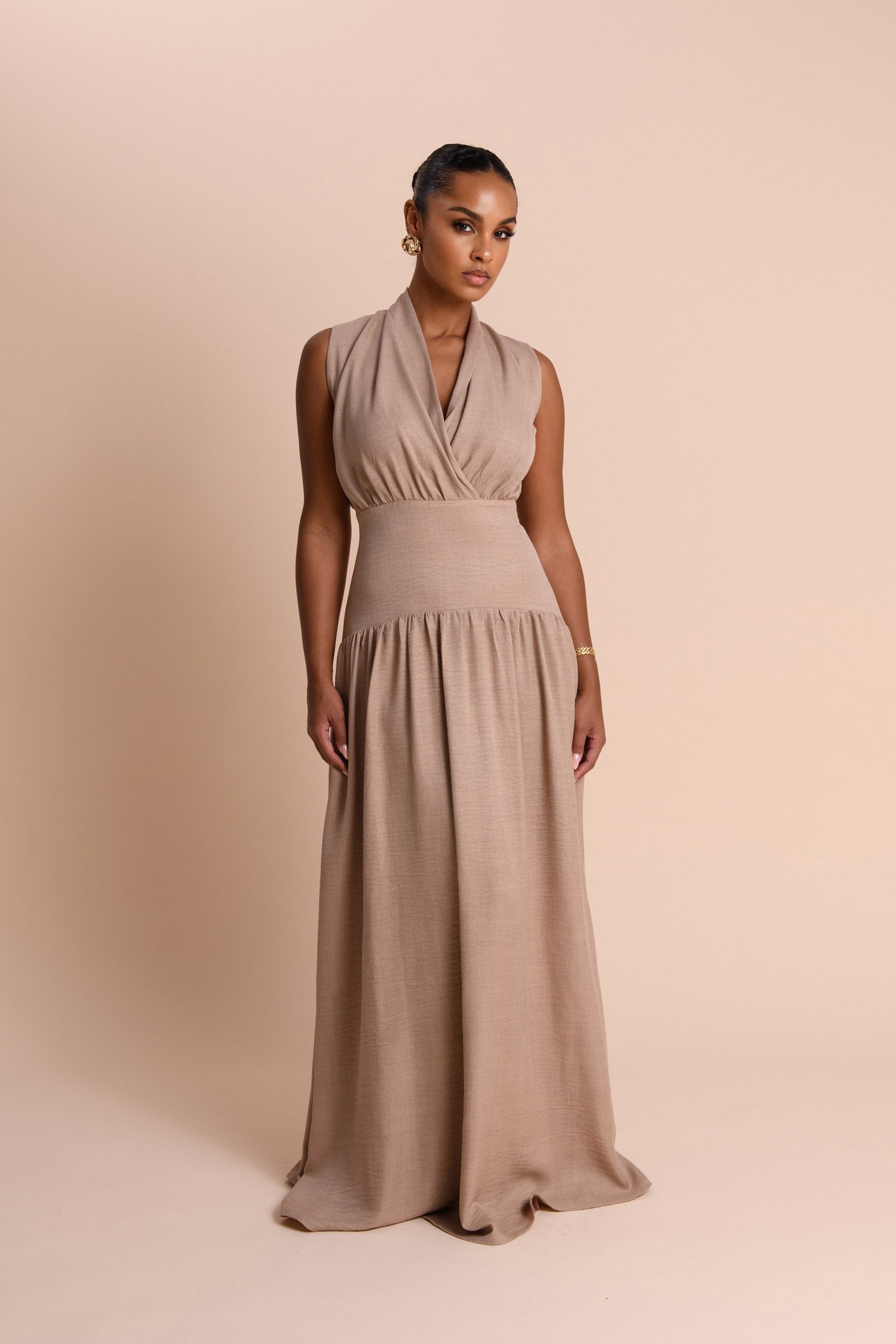 Woman wearing a beige sleeveless gown against a beige background