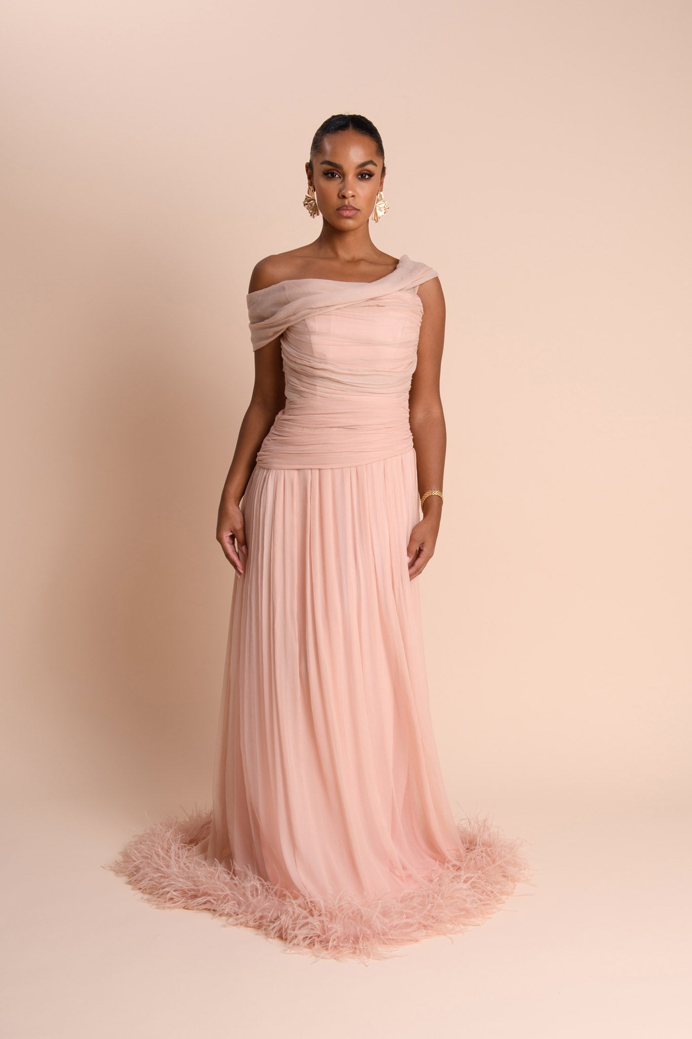 Woman wearing a pink one-shoulder gown against a beige background