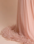 Pink fabric with feather trim against a beige background