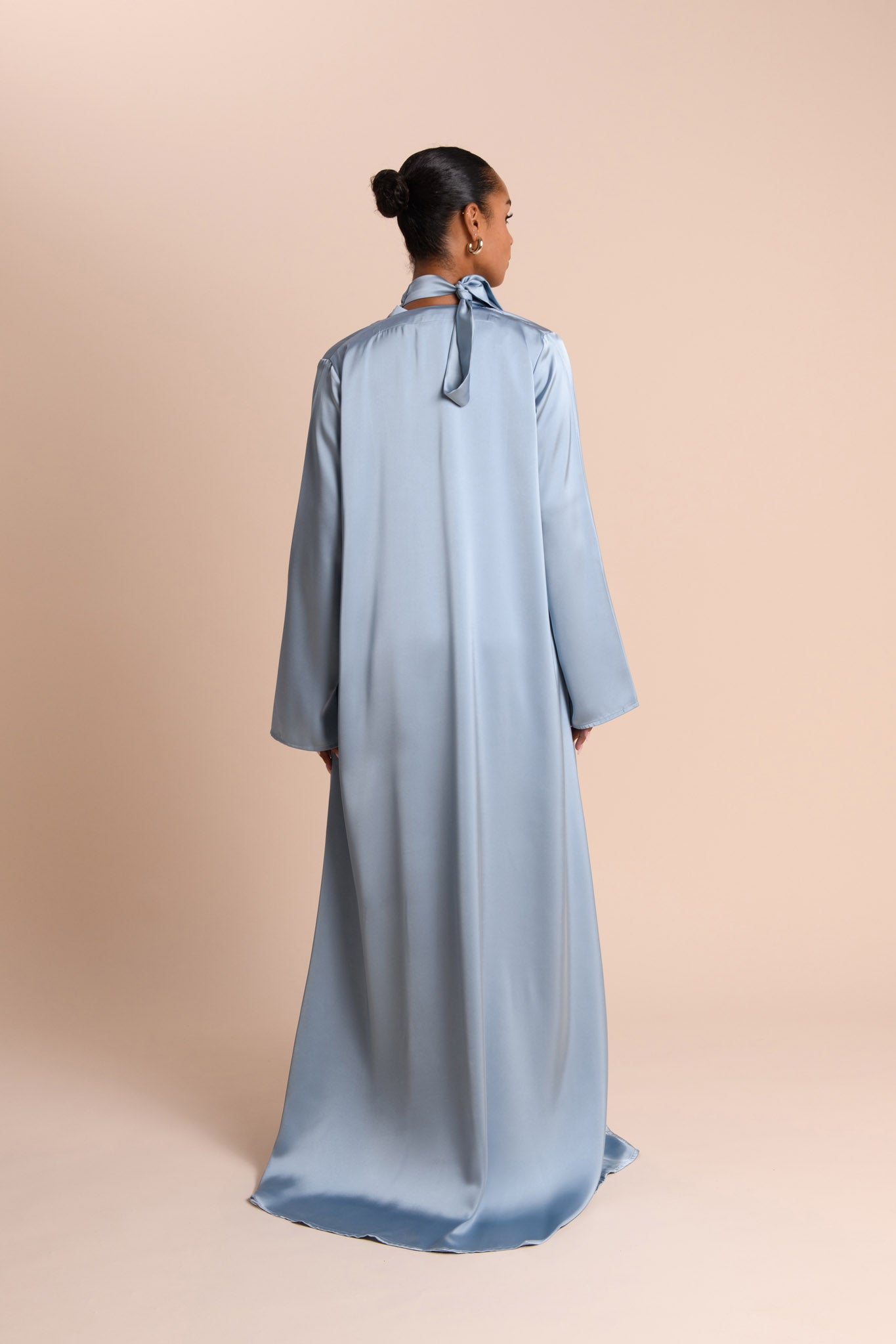 Woman wearing a light blue Abaya on a beige background