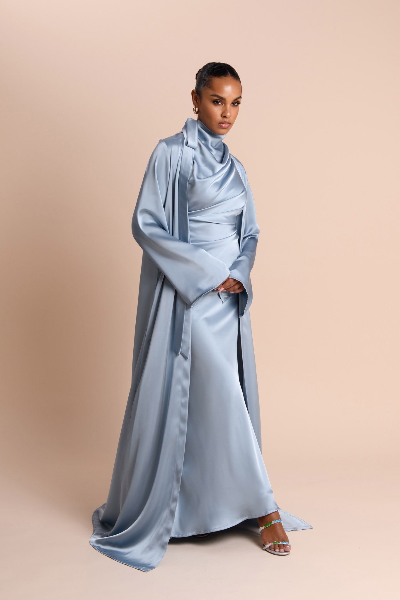 Woman wearing a light blue satin dress against a beige background