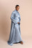 Woman wearing a light blue satin dress against a beige background